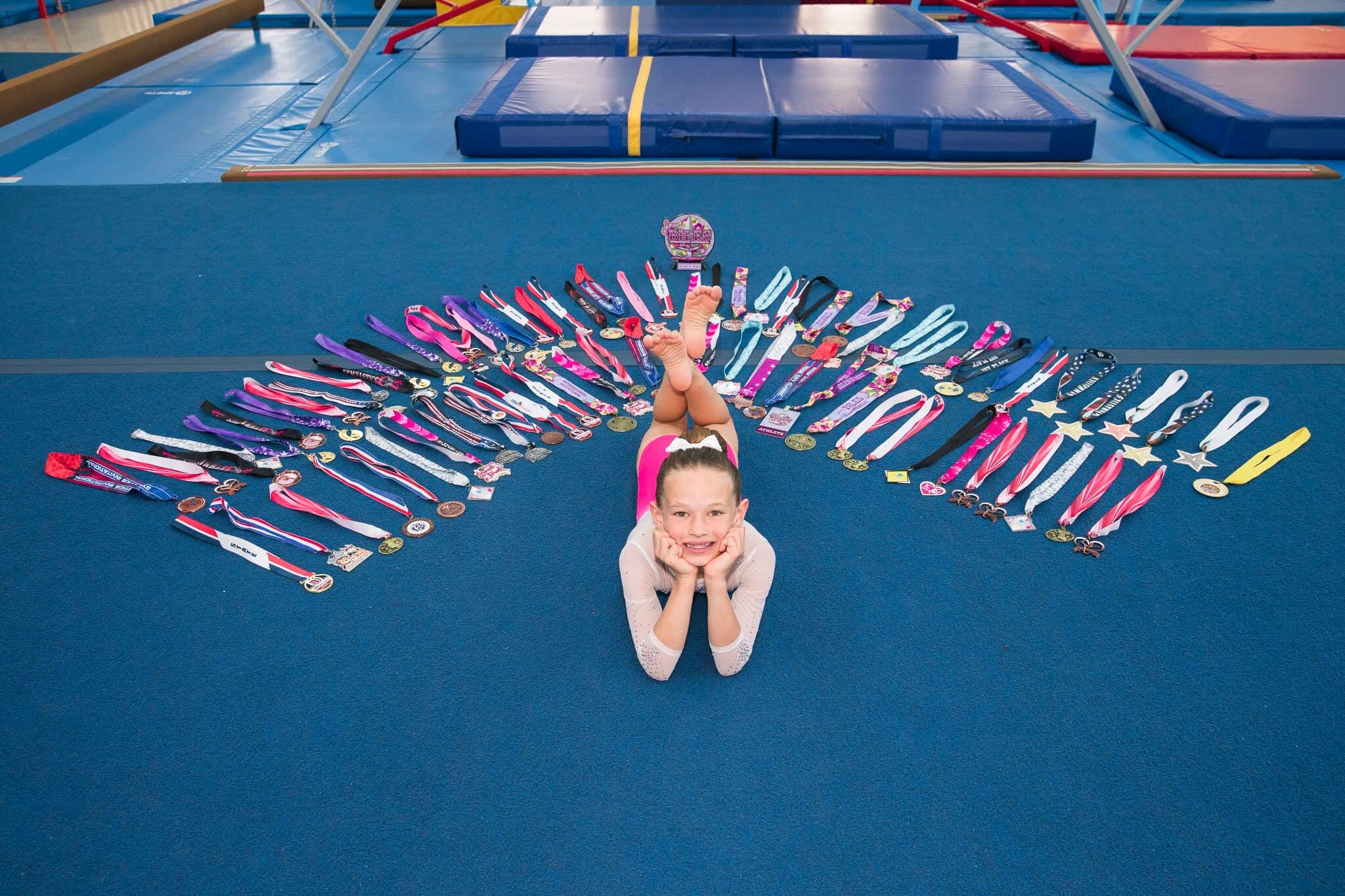 Anastasia lying on the gym floor with her medals spread around her