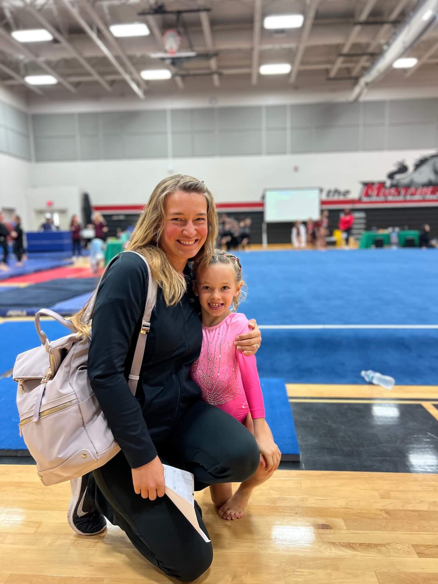 An adult hugging a child at a gymnastics competition