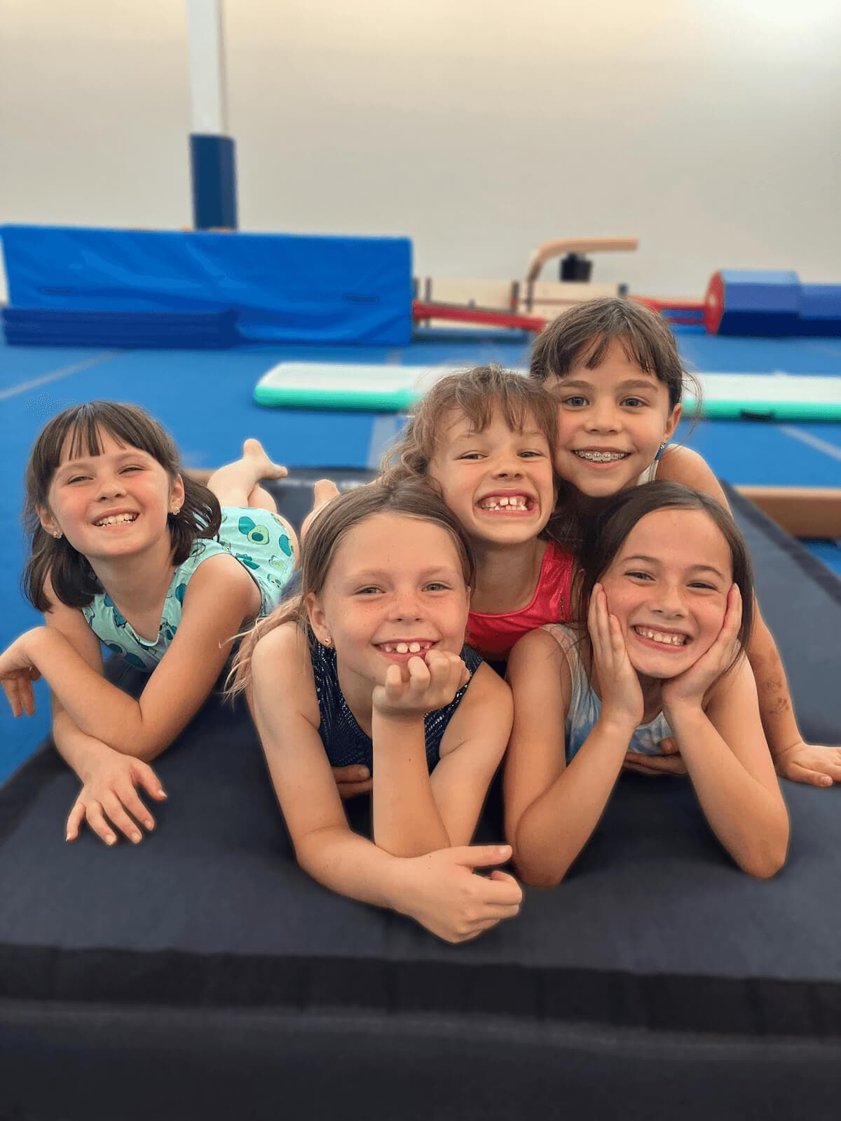 Five girls smiling together in a gymnastics class