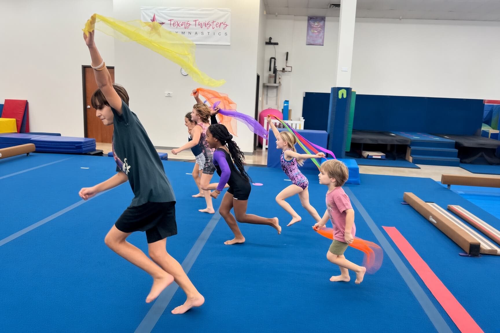 Campers running across the floor with colorful scarves