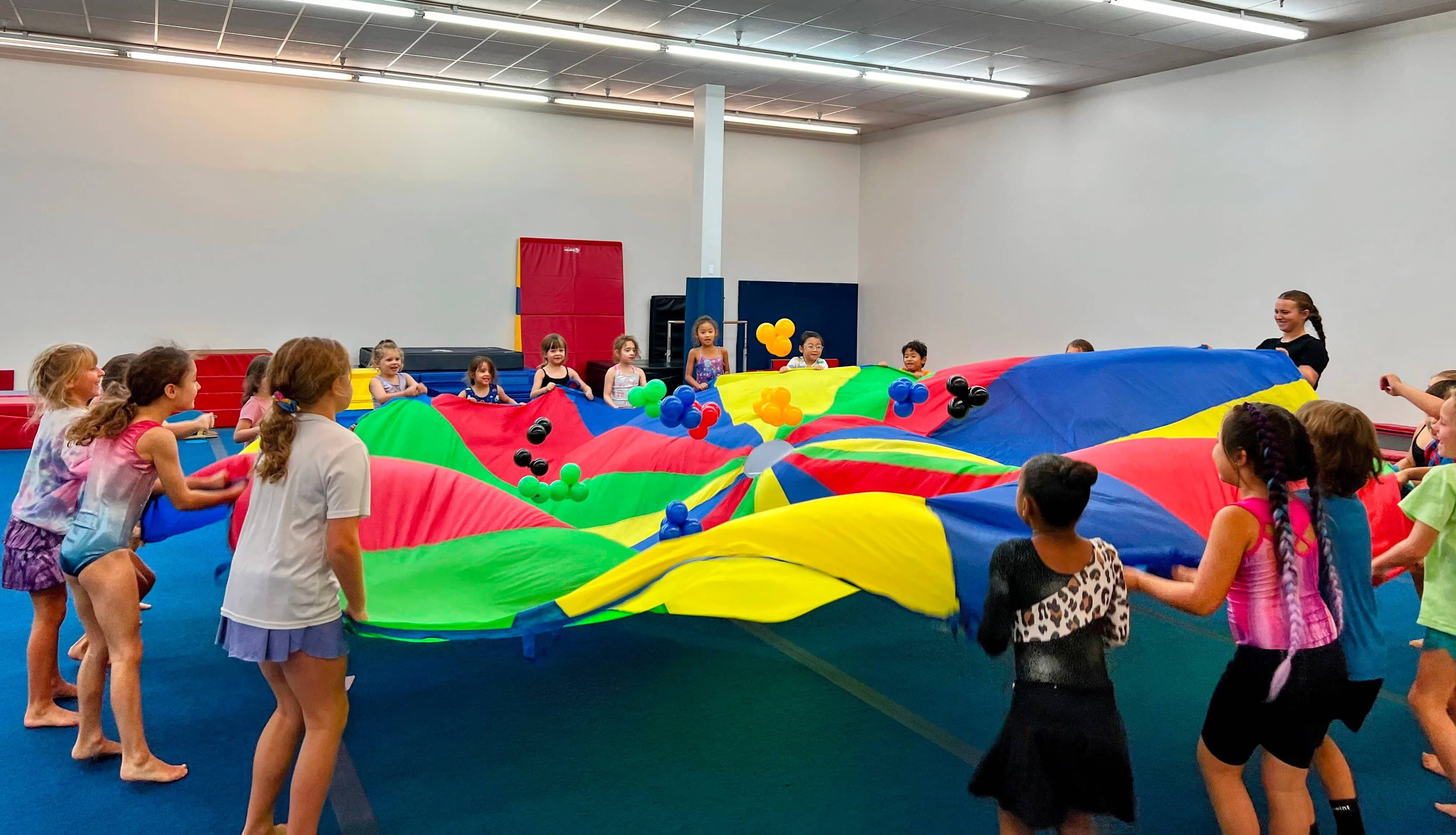 Campers playing with a parachute on the gym floor